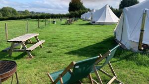 a group of tents and a table and a chair at Home Farm Radnage Glamping Bell Tent 2, with Log Burner and Fire Pit in Radnage