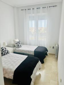 1 dormitorio con 2 camas y ventana en Terrazas golf, en Alicante