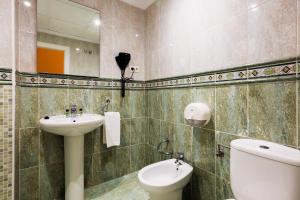 une salle de bain avec un lavabo, des toilettes et un miroir dans l'établissement Hotel Tuto, à Torrevieja