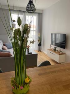 a vase with plants on a table in a living room at APARTAMENT AURA RYBAKI in Gdańsk