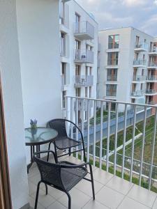 a balcony with two chairs and a table and a building at APARTAMENT AURA RYBAKI in Gdańsk