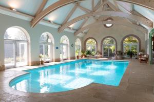 an indoor swimming pool with blue water in a room with windows at Château de Saint Germain du Plain in Saint-Germain-du-Plain