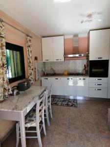 een keuken met witte kasten en een tafel met stoelen bij My Nest in Arzachena