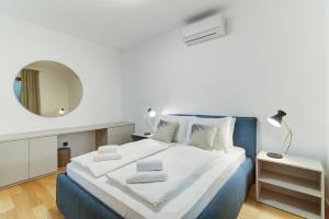 una camera da letto bianca e blu con un letto e uno specchio di Mare Sano apartment #5 a Opatija