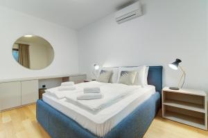 una camera da letto bianca e blu con un letto e uno specchio di Mare Sano apartment #5 a Opatija