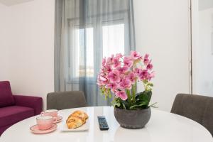 a table with a vase of pink flowers and pastries at Apartments Marina in Bibinje