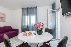 een woonkamer met een witte tafel en een paarse bank bij Apartments Marina in Bibinje