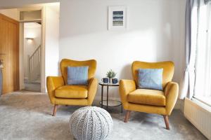 two yellow chairs and a table in a room at The Penthouse in Llandudno