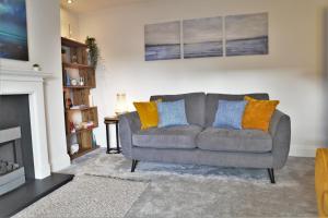 a living room with a gray couch with orange and blue pillows at The Penthouse in Llandudno