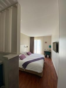 a hotel room with a bed and a television at The Originals Boutique, Hôtel Cassitel, Cassis in Cassis