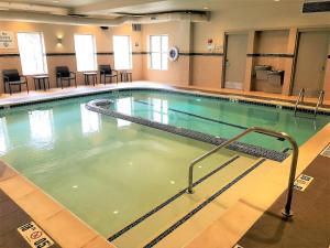 een zwembad met groen water in een gebouw bij Holiday Inn Express & Suites Plymouth - Ann Arbor Area, an IHG Hotel in Plymouth