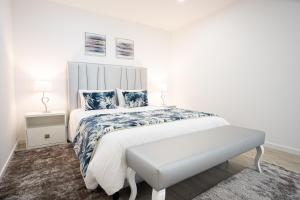 a white bedroom with a bed and a bench at Casa Fonte Nova in Nazaré