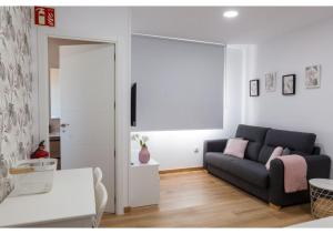 un soggiorno con divano nero e cuscini rosa di Apartamento Felisa A a San Vicente de la Barquera