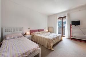 ein weißes Schlafzimmer mit 2 Betten und einem TV in der Unterkunft Casa Angela in San Felice del Benaco