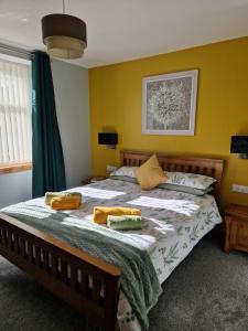 a bedroom with a large bed with yellow walls at Deeside Holiday Cottages in Dinnet