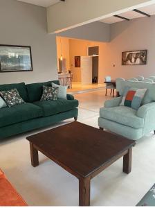 a living room with green couches and a coffee table at Leopards Hill, Lusaka family home in beautiful nature in Mwambula