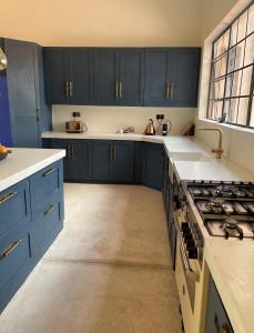 a large kitchen with blue cabinets and a stove at Leopards Hill, Lusaka family home in beautiful nature in Mwambula