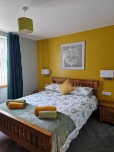 a bedroom with a large bed with yellow walls at Deeside Holiday Cottages in Dinnet