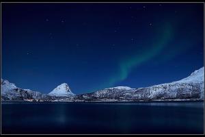 una imagen de la aurora boreal sobre una montaña en Villa Hegge - Design Cabin with fab view, en Sjøvegan