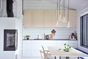 cocina con armarios blancos y mesa en Villa Hegge - Design Cabin with fab view, en Sjøvegan