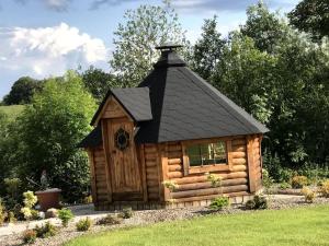 uma cabana de madeira com um telhado preto em Fermanagh lakeside Self Catering em Corranny