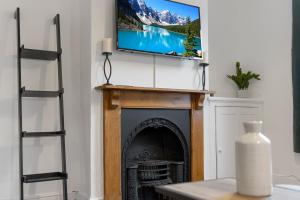 a living room with a fireplace with a television above it at Church View II by Staytor Accommodation in Exeter