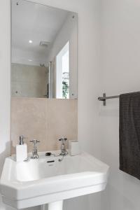 a bathroom with a white sink and a mirror at Church View II by Staytor Accommodation in Exeter