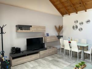 een woonkamer met een tv en een tafel met stoelen bij CASA BEATRIZ in La Orotava