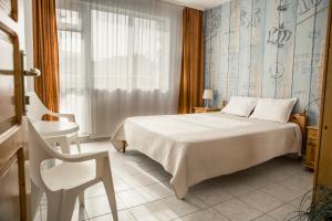 a bedroom with a bed and a chair and a window at Panorama Chantall-izby,apartmány s výhľadom na more in Ravda
