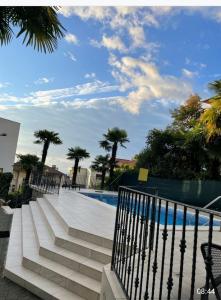een zwembad met trap en palmbomen naast een hek bij Villa Marija in Opatija
