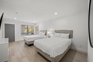 a white bedroom with two beds and a window at Serendipity in Myrtle Beach