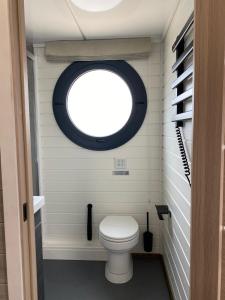 a small bathroom with a toilet with a round window at SeaYou House boat in Offingawier