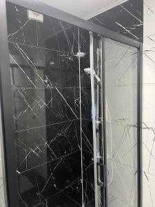 a glass door of a shower with a black wall at Kuman Apartments in Kumanovo