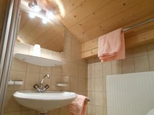 a bathroom with a white sink and a wooden ceiling at Aclavaldafur Apart in Nauders