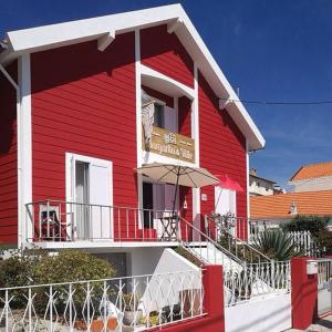 a red building with an umbrella in front of it at Margarita´s Ville in Costa Nova