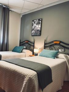 a bedroom with two beds and a wall at Hostal Paulino in Trujillo