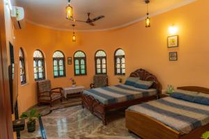 twee bedden in een kamer met oranje muren en ramen bij Casa de Alnena in Benaulim