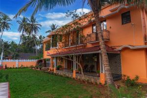 an orange house with a palm tree in front of it at Casa de Alnena in Benaulim