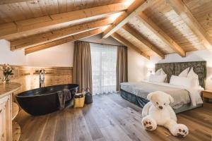 a bedroom with a large bed and a bath tub at Alpin Garden Luxury Maison & SPA - Adults Retreat in Ortisei