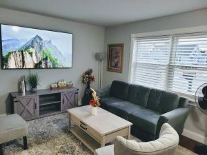 een woonkamer met een groene bank en een tv bij No Chores, house with private parking, yard in West Seneca