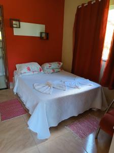 a bedroom with a white bed with a red wall at Pousada Sítio da Floresta in Sana