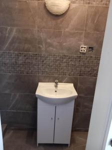 a bathroom with a white sink and a tile wall at Ubytovanie Tri sestry in Hrabušice