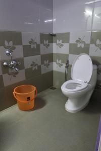 a bathroom with a toilet and an orange bucket at Ammukutty's Cottage in Munnar