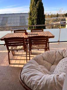 - une table en bois avec 2 chaises et un lit pour chien sur la terrasse dans l'établissement Rias Apart II, à Vila Real de Santo António