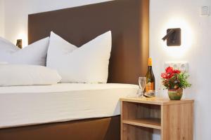 a bed with white pillows and a bottle of wine on a table at Das Salzburgblick in Ainring
