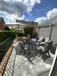 un patio con sillas, una mesa y una sombrilla en Ferienhaus Hildchen an der Osterheide en Schneverdingen