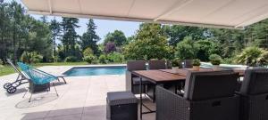 une terrasse avec une table, des chaises et une piscine dans l'établissement Magnifique villa 5 etoiles avec piscine privee parc 2 ha, à La Limouzinière