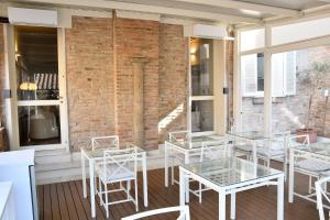 a patio with white tables and chairs and a brick wall at Avanguardia Art Club in Ferrara