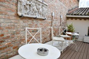 eine Terrasse mit einem weißen Tisch und Stühlen an einer Ziegelwand in der Unterkunft Avanguardia Art Club in Ferrara