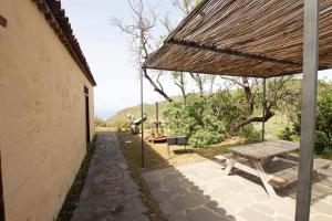 un patio con mesa de picnic y techo de paja en Casa rural cerca de la costa de La Laguna en La Laguna